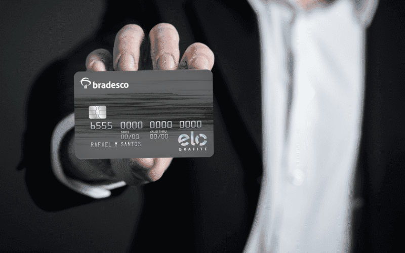 Cartão Bradesco Seguros Elo Grafite: Programa de Relacionamento Bradesco Seguros e Clube de Vantagens Bradesco Seguros! 1 um homem segurando o cartao Bradesco Elo Grafite Platinum