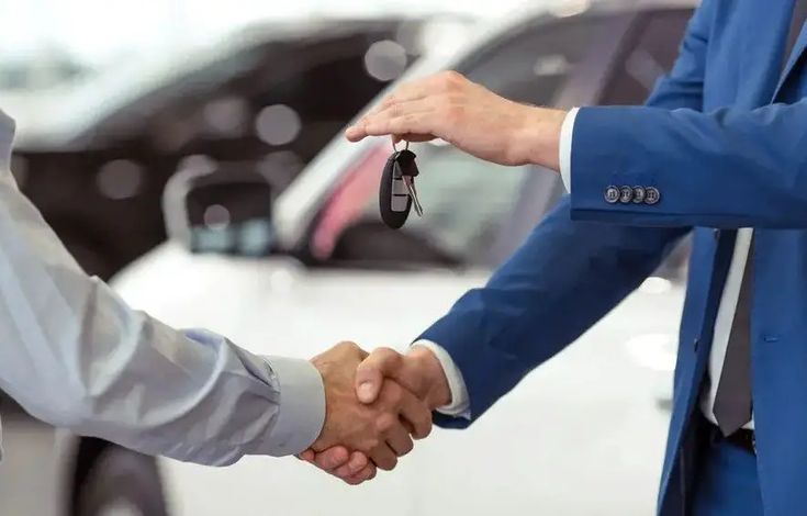 Cliente aperta a mão de vendedor enquanto recebe a chave do veículo, simbolizando a conclusão de um financiamento de carro.