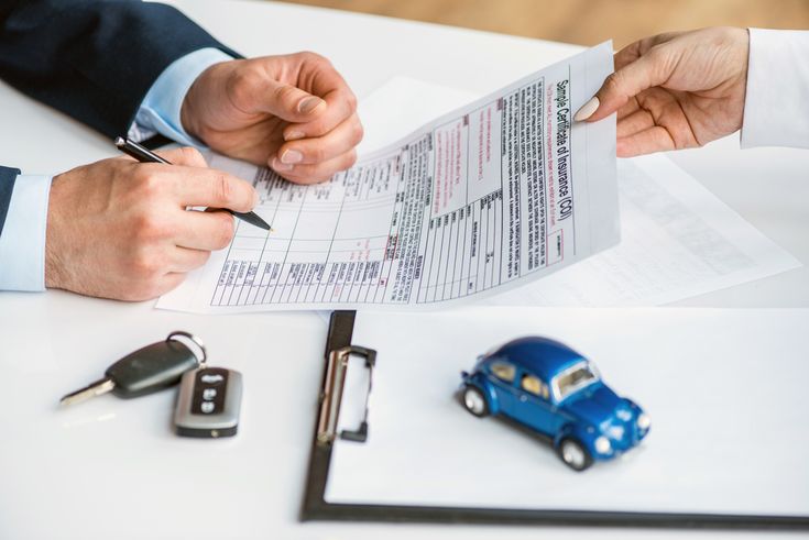 Pessoa assinando contrato de compra com chave de carro e miniatura sobre a mesa, representando a formalização de um financiamento de carro.