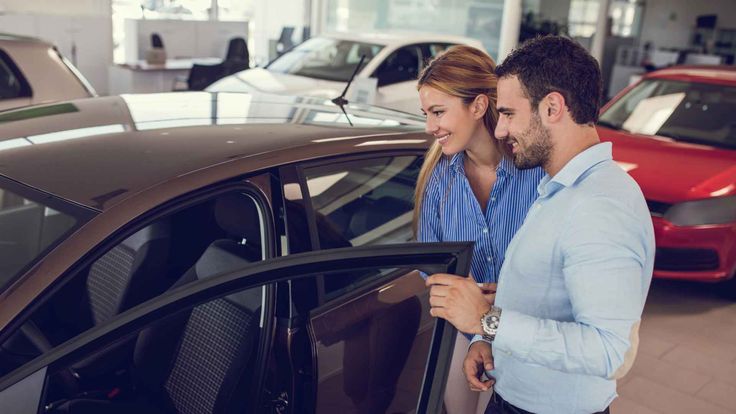 Casal observa veículo em concessionária durante processo de escolha, representando o início de um financiamento de carro.