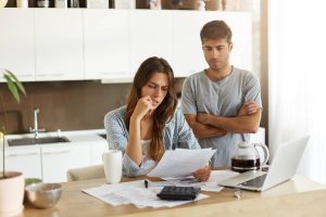 Casal preocupado analisando contas e buscando soluções financeiras em casa, representando a dificuldade de conseguir um empréstimo para negativado.