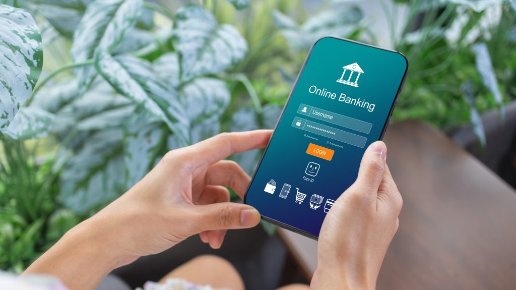 Conta digital que rende mais que a poupança: melhores opções em 2025 1 Pessoa segura um smartphone com a tela de login de um aplicativo de banco digital, simbolizando o acesso a uma conta digital que rende mais que a poupança.