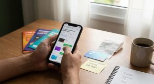 Pessoa usando celular para comparar opções de cartão de crédito com limite de 500 reais para negativado, com cartões sobre a mesa, anotações de limite, recibo e xícara de café em ambiente doméstico.