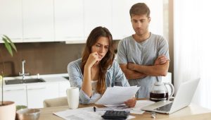 Casal preocupado analisando contas e buscando soluções financeiras em casa, representando a dificuldade de conseguir um empréstimo para negativado.