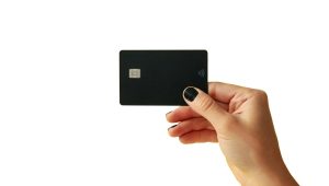 Pessoa segurando um cartão de crédito black premium com chip e tecnologia contactless, representando os melhores cartões black