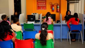 Sala de espera de um atendimento público, com pessoas sentadas aguardando orientação sobre benefícios sociais, ilustrando situações em que o Bolsa Família bloqueado recebe atrasado.