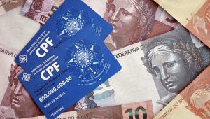 Cartões de CPF sobre notas de real, representando consulta e verificação de dados financeiros para entender como saber se tenho direito a indenização do Serasa.