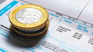 Moedas de um real sobre uma conta de luz, ilustrando informações sobre Crefaz empréstimo na conta de luz e serviços financeiros vinculados à fatura.
